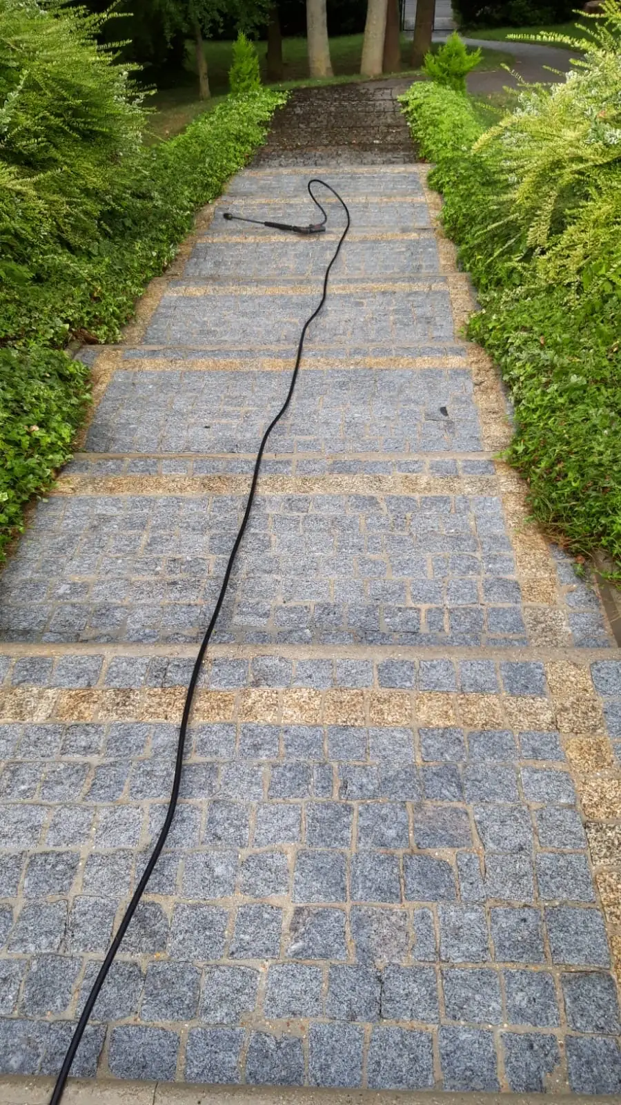 Escalier de jardin en pavés de granit, la lance du nettoyeur posée sur les marches