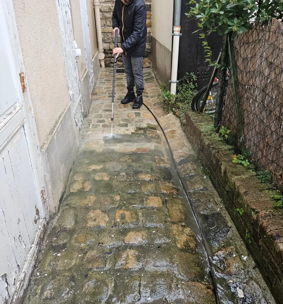 Passage pavé le long d’une maison, nettoyé à la lance haute pression