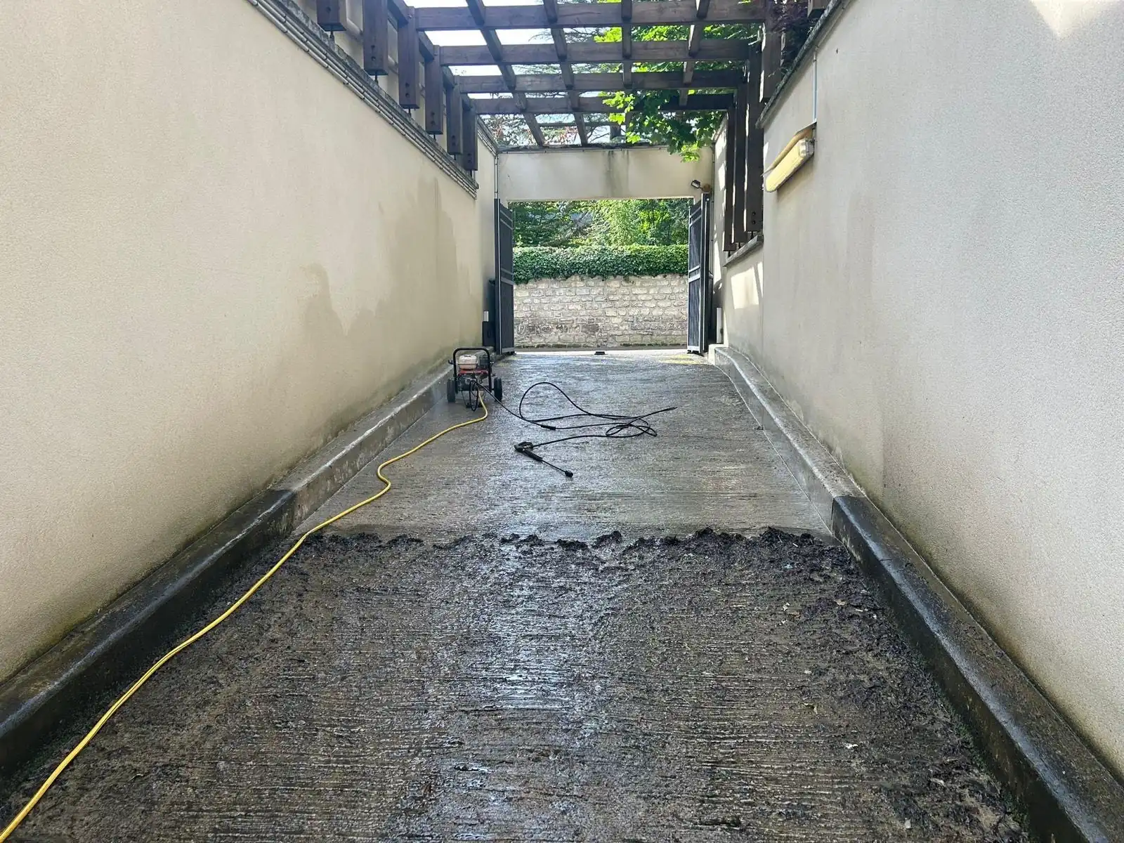 Rampe d’accès à un parking souterrain en cours de lavage à la haute pression, entre deux murs blancs